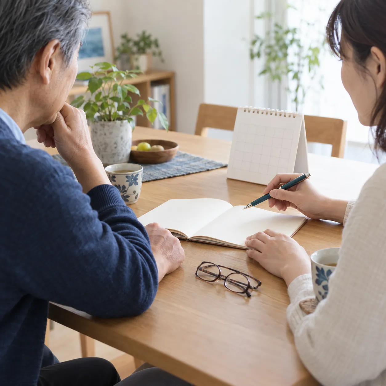 AIで制作した編集用イメージ。自宅のテーブルで親子が白紙のノートとカレンダーを見ながら話している。実際の年金書類ではない。